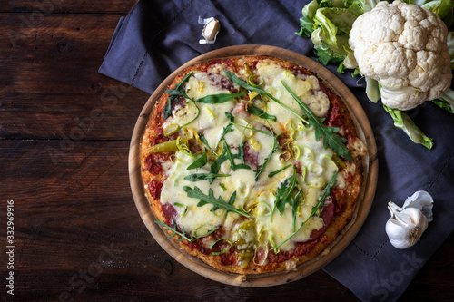 Fotografie Pizza with a crust from shredded cauliflower on a dark rustic wooden table, alte