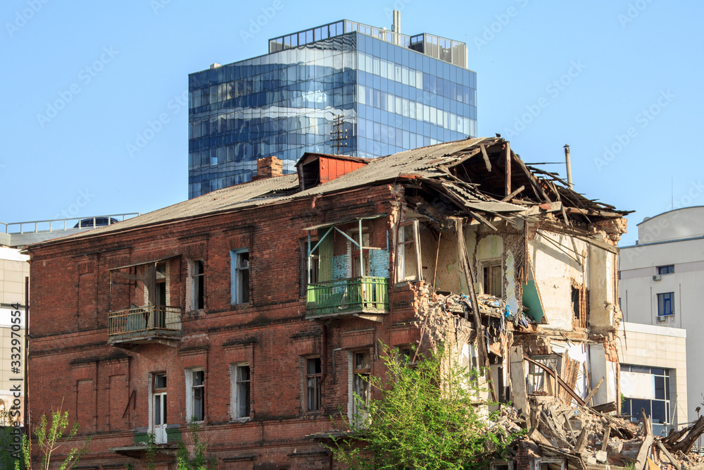 House demolished against the backdrop of a modern glass building House demolished against the backdrop of a modern glass building