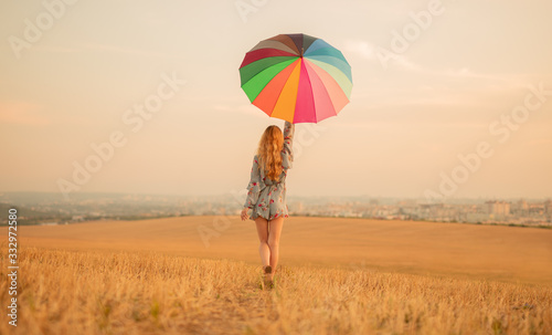Stylish woman with umbrella walking in golden field