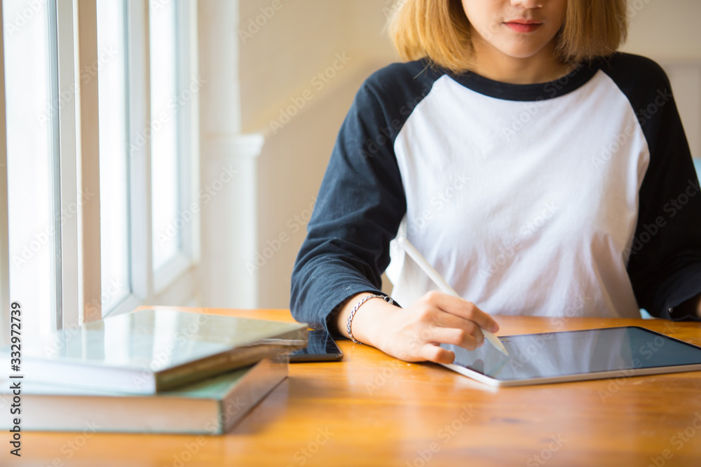 Asian beautiful woman Freelance work with a tablet in the window of her house happily in Morning warm light Asian beautiful woman Freelance work with a tablet in the window of her house happily in Morning warm light