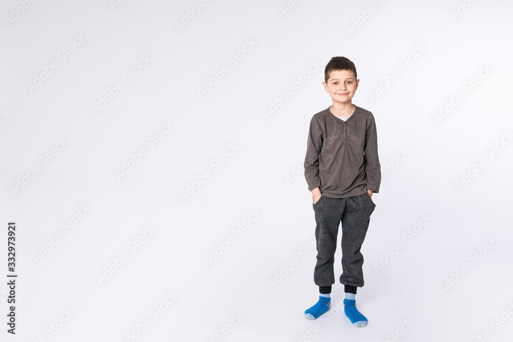 Little attractive boy in casual clothes holds his hands in pockets and looking at the camera, isolated on white background Little attractive boy in casual clothes holds his hands in pockets and looking at the camera, isolated on white background