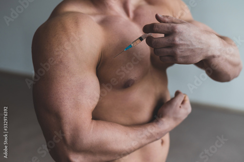 Close-up of a male torso. Unrecognizable shirtless bodybuilder man puts himself an injection of testosterone. Faceless athlete takes dope. photo