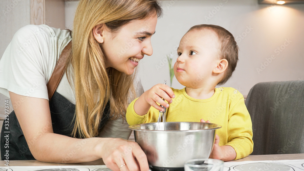Mother and baby son preparing food together in kitchen. Happy family cooking and having fun. Home acitvity and education concept. Mother and baby son preparing food together in kitchen. Happy family cooking and having fun. Home acitvity and education concept.