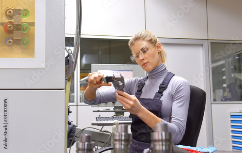 A young woman works as a computerized  numerical control engineer. She is seen at her workplace wearing a blue overall. 