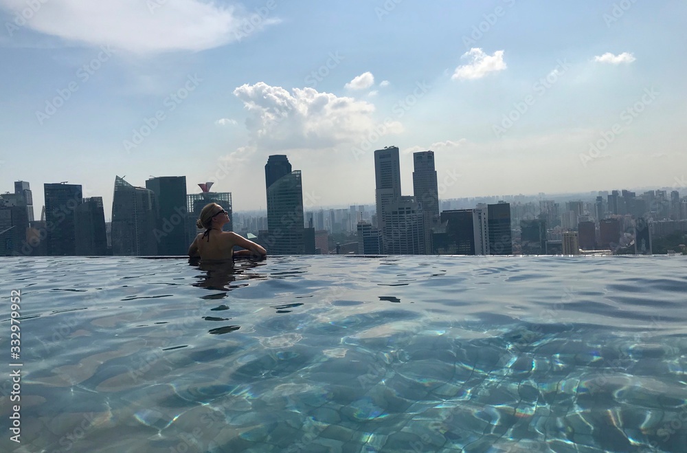 Obraz premium Blond woman in rooftop pool on skyscraper, with skyline in background, Singapore, South East Asia
