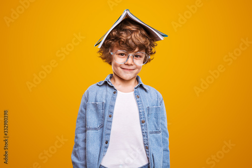 Positive schoolboy with book and glasses photo