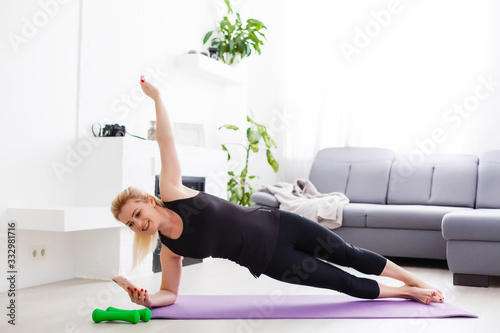a thin European girl doing stretching exercises at home on a yoga mat, rays of light shine from the window. flare. quarantine sport.