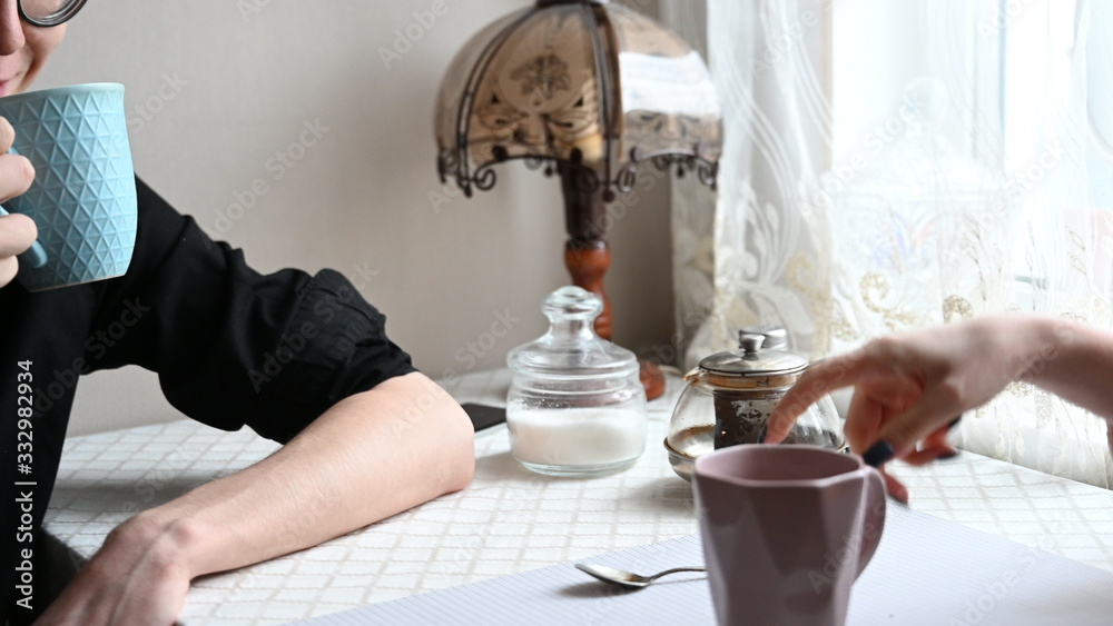 Fototapeta premium a guy and a girl sit at home in quarantine and drink tea in the kitchen