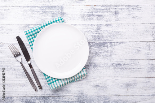 Empty white plate and cutlery on wooden background. Copy space. Top view