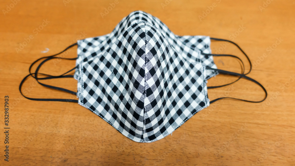 Mask from black and white plaid and nano fabric on wooden desk, Housewife made cloth face protective mask handmade from tartan cloth,Mask for protection nose and mouth on wood table background