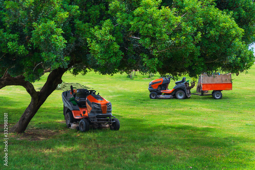 Lawn mower machines on green field. Summer garden ritual photo