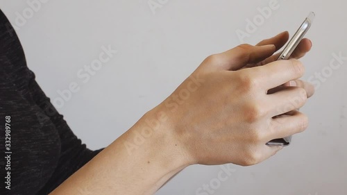 Female hands using mobile phone and scrolling against gray wall background