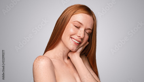 Young redhead woman enjoying softness of skin