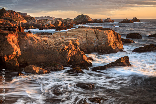 the glow of sunset lights the rocks along the coast of California