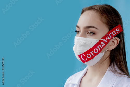 Doctor woman with surgical mask pointing to red paper with mesaage Coronavirus on blue background. World Health Organization WHO introduced new official name for Coronavirus disease named COVID-19 photo