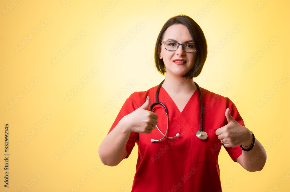 Beautiful woman doctor with stethoscope, wearing red scrubs showing thumbs up with both hands Beautiful woman doctor with stethoscope, wearing red scrubs showing thumbs up with both hands