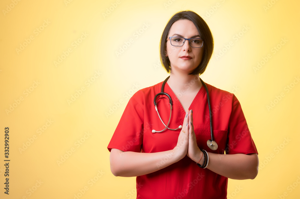 Beautiful woman doctor with stethoscope, wearing red scrubs praying Beautiful woman doctor with stethoscope, wearing red scrubs praying