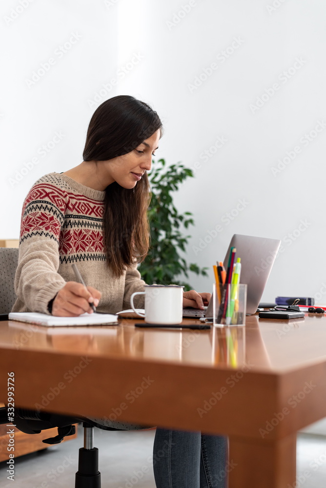 Young freelancer working from a makeshift home office connected to the internet with a laptop and a phone during the period of global confinement Young freelancer working from a makeshift home office connected to the internet with a laptop and a phone during the period of global confinement
