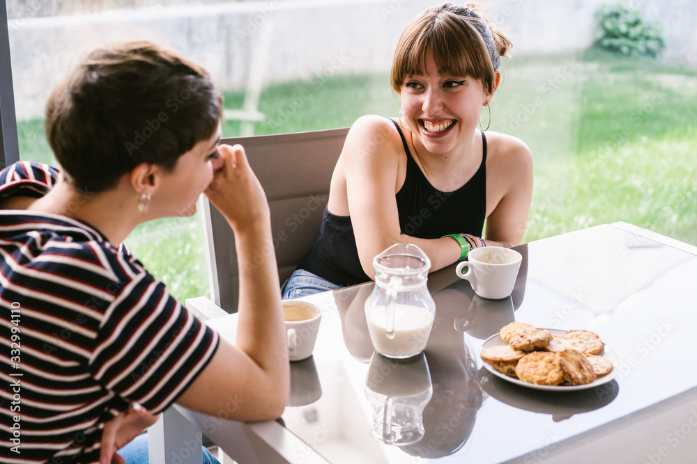 Two Girls Talking And Smiling While Having A Coffee At Home. Two Girls Talking And Smiling While Having A Coffee At Home.