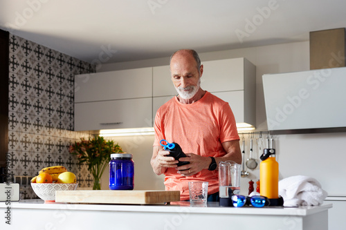 Active senior man with protein drink after exercising photo