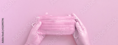 Fototapeta Naklejka Na Ścianę i Meble -  Pink protective surgical face mask and woman hands in gloves background, selective focus, banner