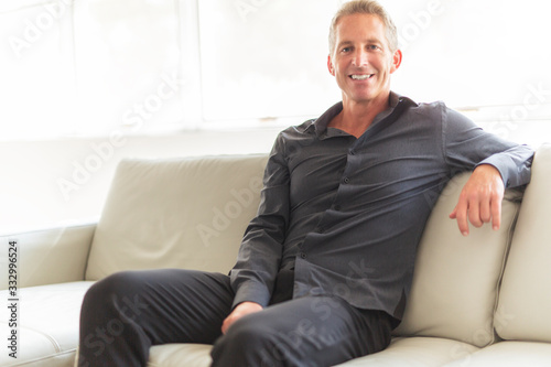 Portrait of single 40s man sitting in sofa photo