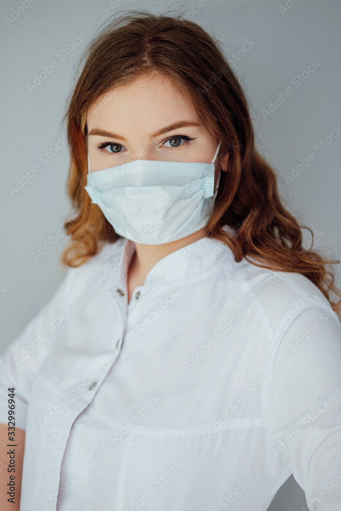 Young woman doctor in a white coat and medical mask. The medicine