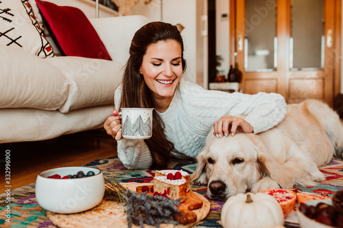 Young woman having a healthy breakfast lying on the floor at home while she is in quarentine during the covid19 crisis accompanied by her golden retriever. Lifestyle. Stay home