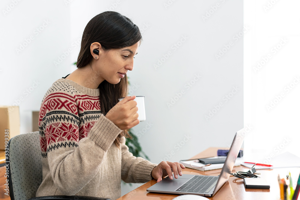 Young freelancer working from a makeshift home office connected to the internet with a laptop and a phone during the period of global confinement Young freelancer working from a makeshift home office connected to the internet with a laptop and a phone during the period of global confinement