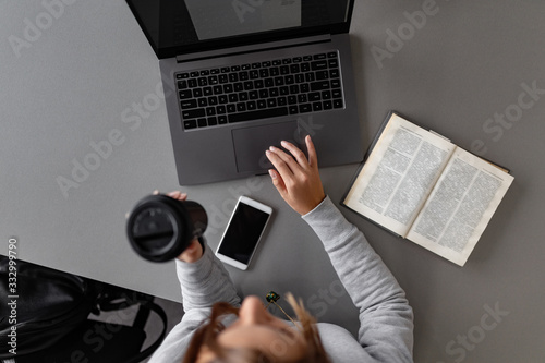 Woman having coffee while studying with laptop