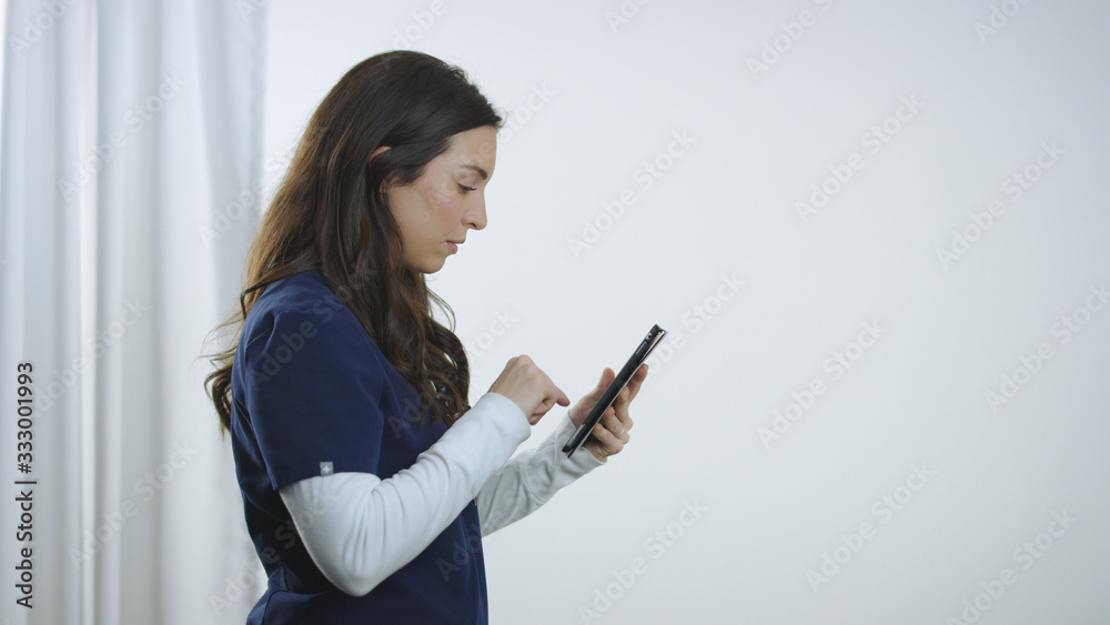 Profile of nurse entering data into tablet device in sterile hospital setting Profile of nurse entering data into tablet device in sterile hospital setting
