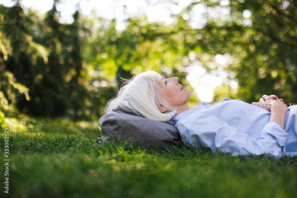 Mature woman lying in the green grass looking up. Mature woman lying in the green grass looking up.