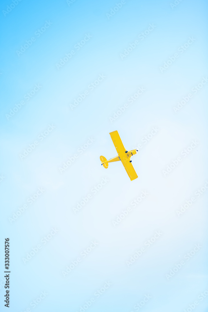 A small yellow plane flying in the sky A small yellow plane flying in the sky