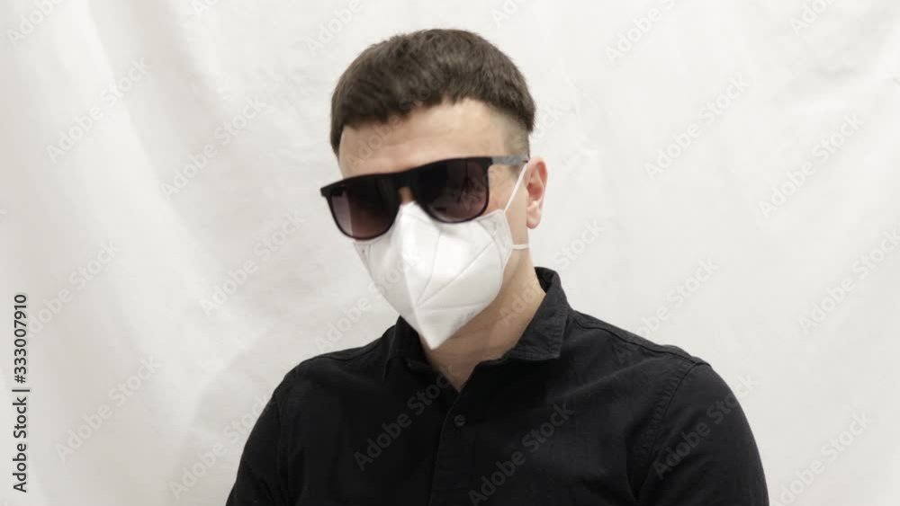 man in a black shirt, sunglasses and a protective white mask respirator on a white background different emotions corona virus man in a black shirt, sunglasses and a protective white mask respirator on a white background different emotions corona virus