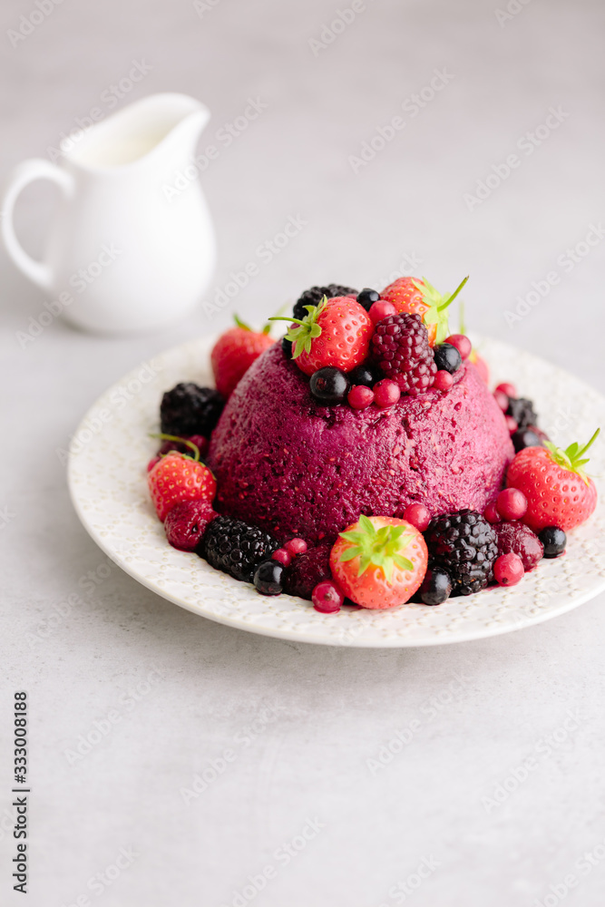 English Summer Pudding on plate with cream behind English Summer Pudding on plate with cream behind
