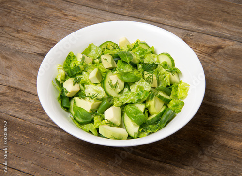 Fotografía Salad with citrus vinaigrette, avocado cucumber green beans and romaine salad in an bowl on a rustic wooden table