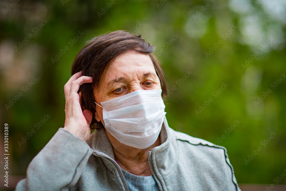 an adult woman, a pensioner, on a walk in a medical mask an adult woman, a pensioner, on a walk in a medical mask