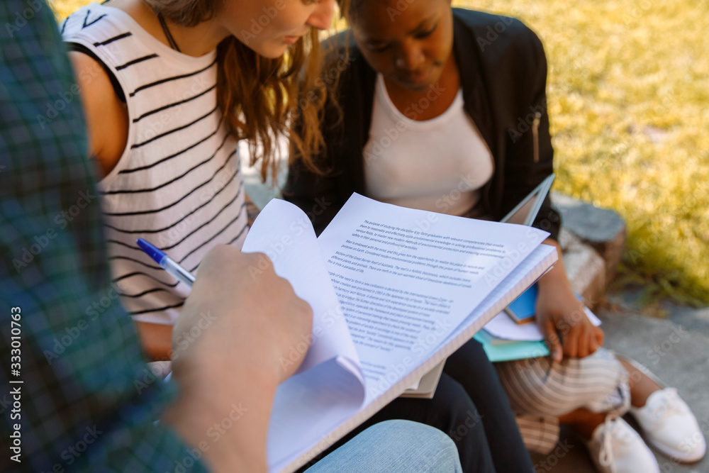 Crop student reading paper near classmates Crop student reading paper near classmates