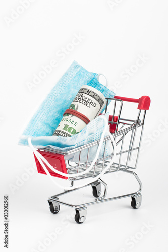 Sale of medical masks. Medical mask in shop trolley with money on white background. Coronavirus concept. 2019 nCoV. © zadorozhna