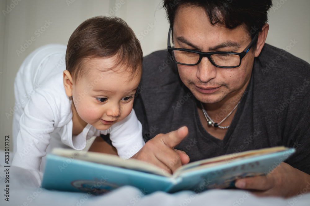 Baby and daddy reading book on the bed Baby and daddy reading book on the bed
