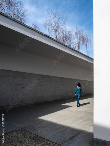 Una joven saliendo de un edificio de arquitectura contempòranea de lineas rectas 