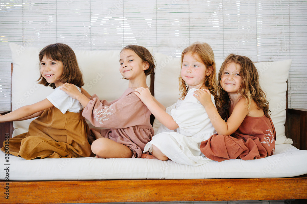 Four little girls about the same age sitting on a sofa one behind another Four little girls about the same age sitting on a sofa one behind another