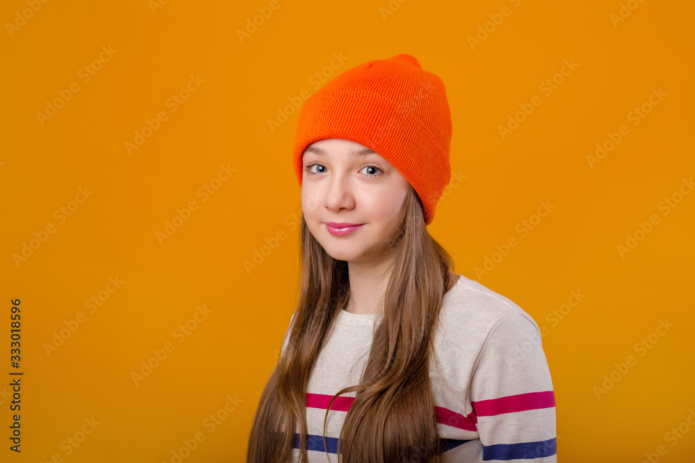 Happy schoolgirl with long hair holds her hands in front on a yellow background