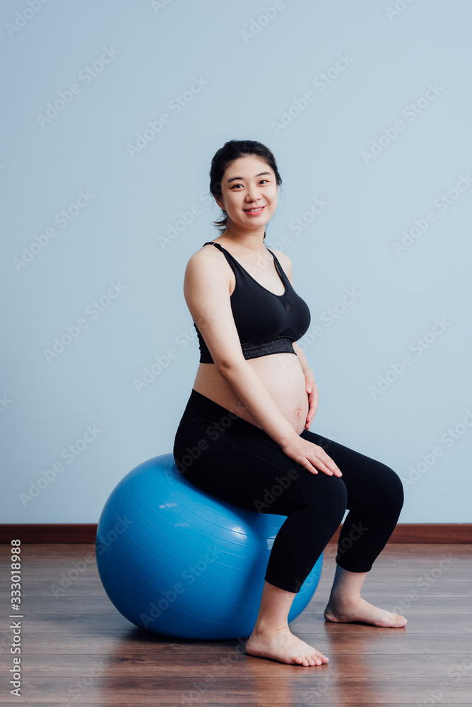 Pregnant woman doing yoga practice and sitting on fitness ball Pregnant woman doing yoga practice and sitting on fitness ball
