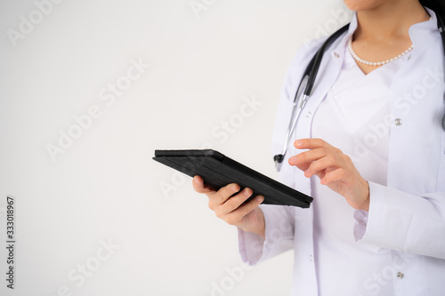 Close up of the hands and electronic tablet of a young girl doctor