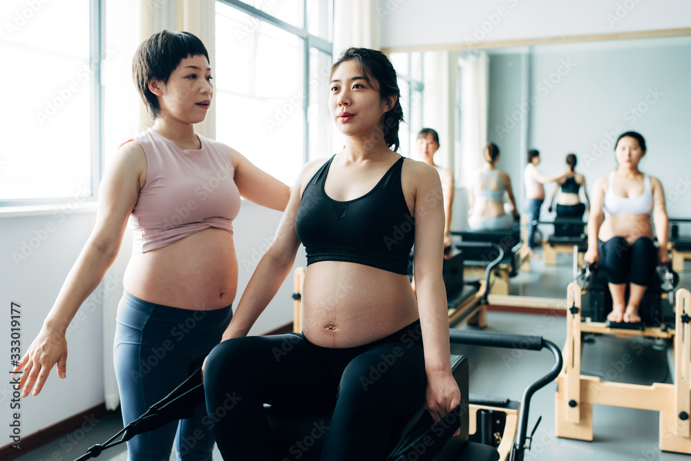 Pregnant woman practicing pilates with equipment reformer Pregnant woman practicing pilates with equipment reformer