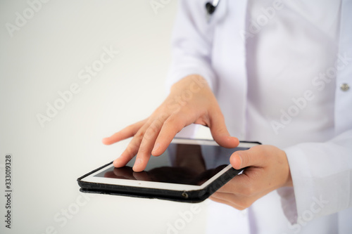 Close up of the hands and electronic tablet of a young girl doctor
