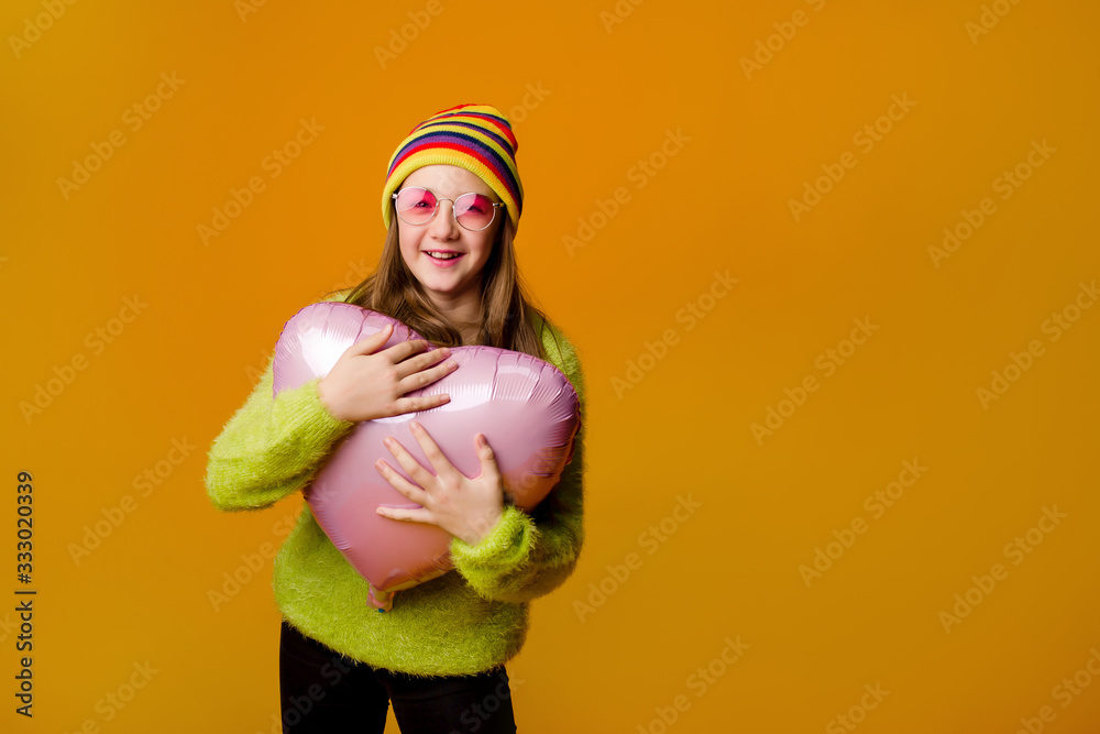 happy teenage girl in sunglasses holds a heart-shaped balloon