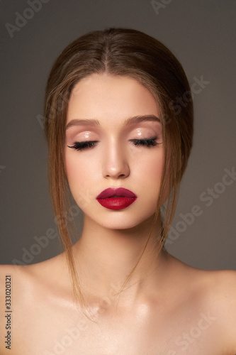  Young girl with red lips and closed eyes on a gray background