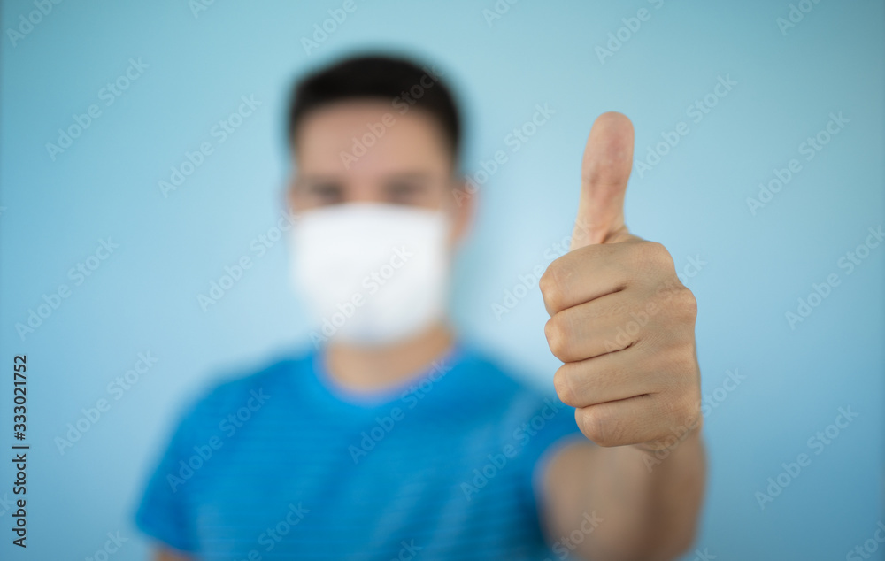 Young man wearing a protective mask with thumbs up. Help stop the spread of Coronavirus by protecting yourself concept. Young man wearing a protective mask with thumbs up. Help stop the spread of Coronavirus by protecting yourself concept.